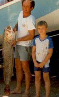 A young boy on the harbour wall with his father and the day's catch